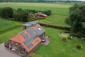 A large house with a red roof and solar panels, surrounded by green fields and trees. - Holiday apartment in Dunum with swimming pool (Dunum)