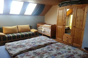 A room with a loft bed, a sofa, a crib, and a wooden wardrobe. - Holiday apartment in Dunum with swimming pool (Dunum)