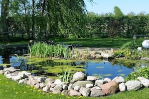 A pond with rocks and plants, surrounded by a grassy area and trees. - Holiday apartment in Dunum with swimming pool (Dunum)