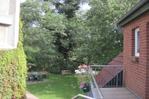 A brick building with a small garden area, a bench, and a metal railing. - Crane at the Röbel/Müritz water tower (Röbel)