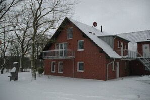 A red brick house with a snow-covered roof and a balcony. - Crane at the Röbel/Müritz water tower (Röbel)