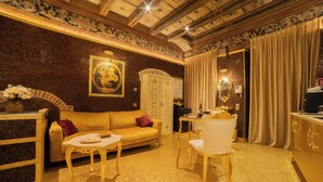 A luxurious room with a sofa, a dining table, and a chair. There is a mirror and a cabinet. - The Doge's Secret | Wellness Suite with Private Spa in Verona (Verona)