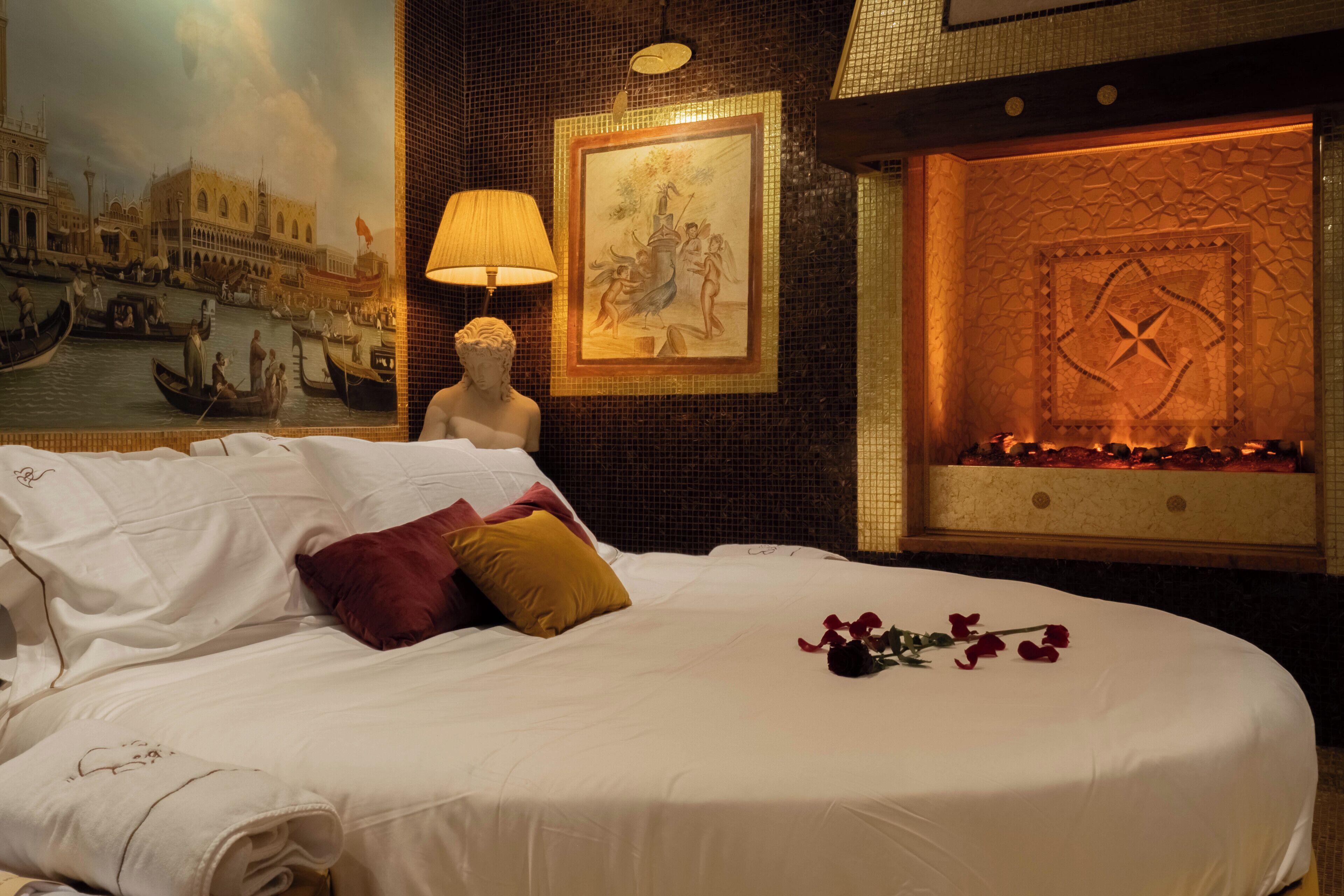 Une chambre d’hôtel avec un lit, un tableau, une statue et une cheminée.