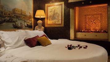 Une chambre d’hôtel avec un lit, un tableau, une statue et une cheminée.