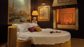 Ein Hotelzimmer mit einem großen Bett, einem Nachttisch, einer Lampe und einem Kamin.