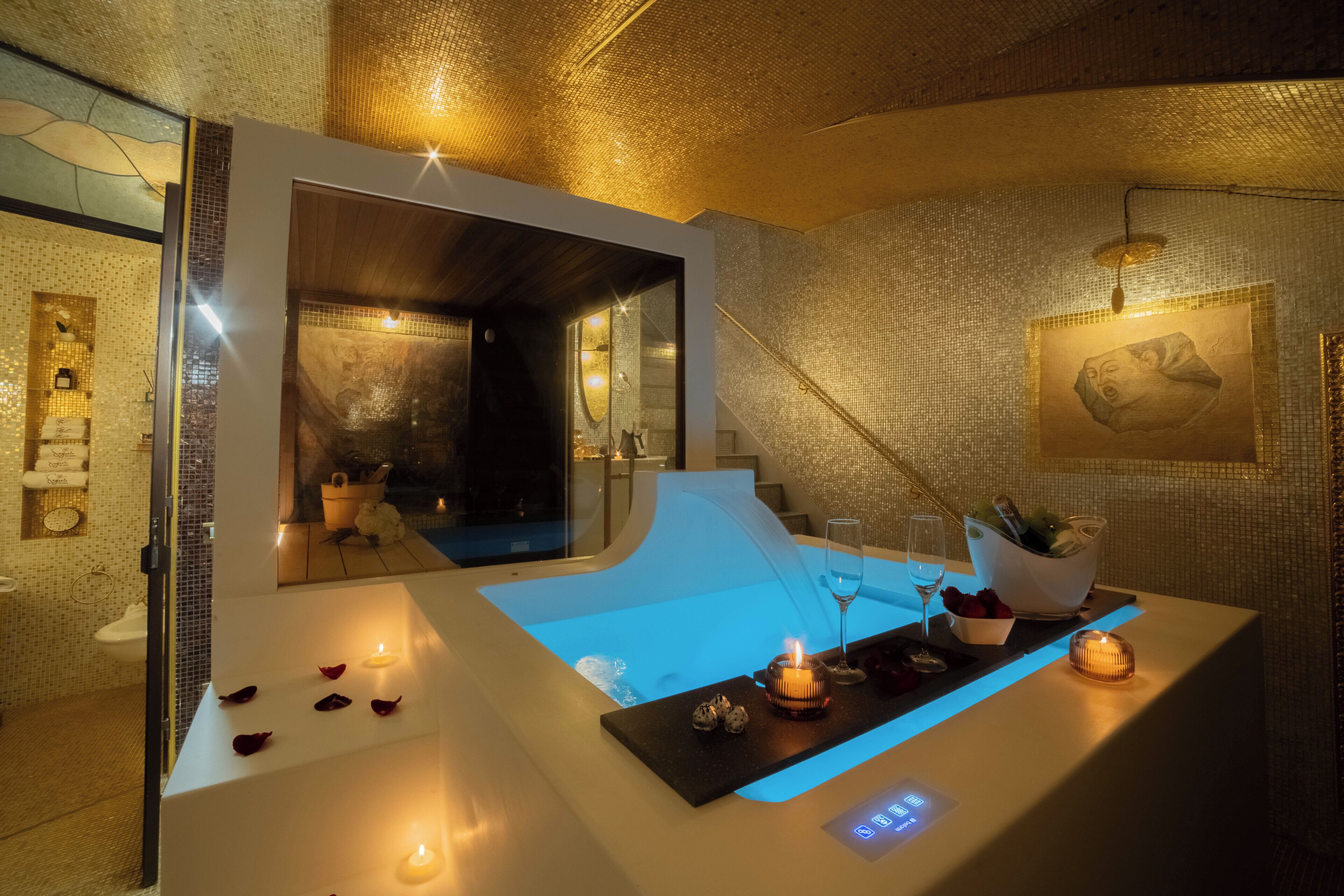 Un baño moderno con un espejo grande, una bañera y un tocador con encimera iluminada en azul.