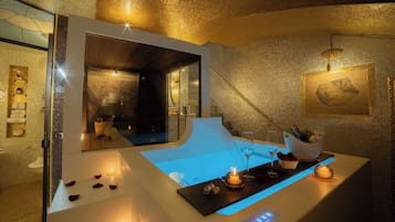 Un baño moderno con un espejo grande, una bañera y un tocador con encimera iluminada en azul.