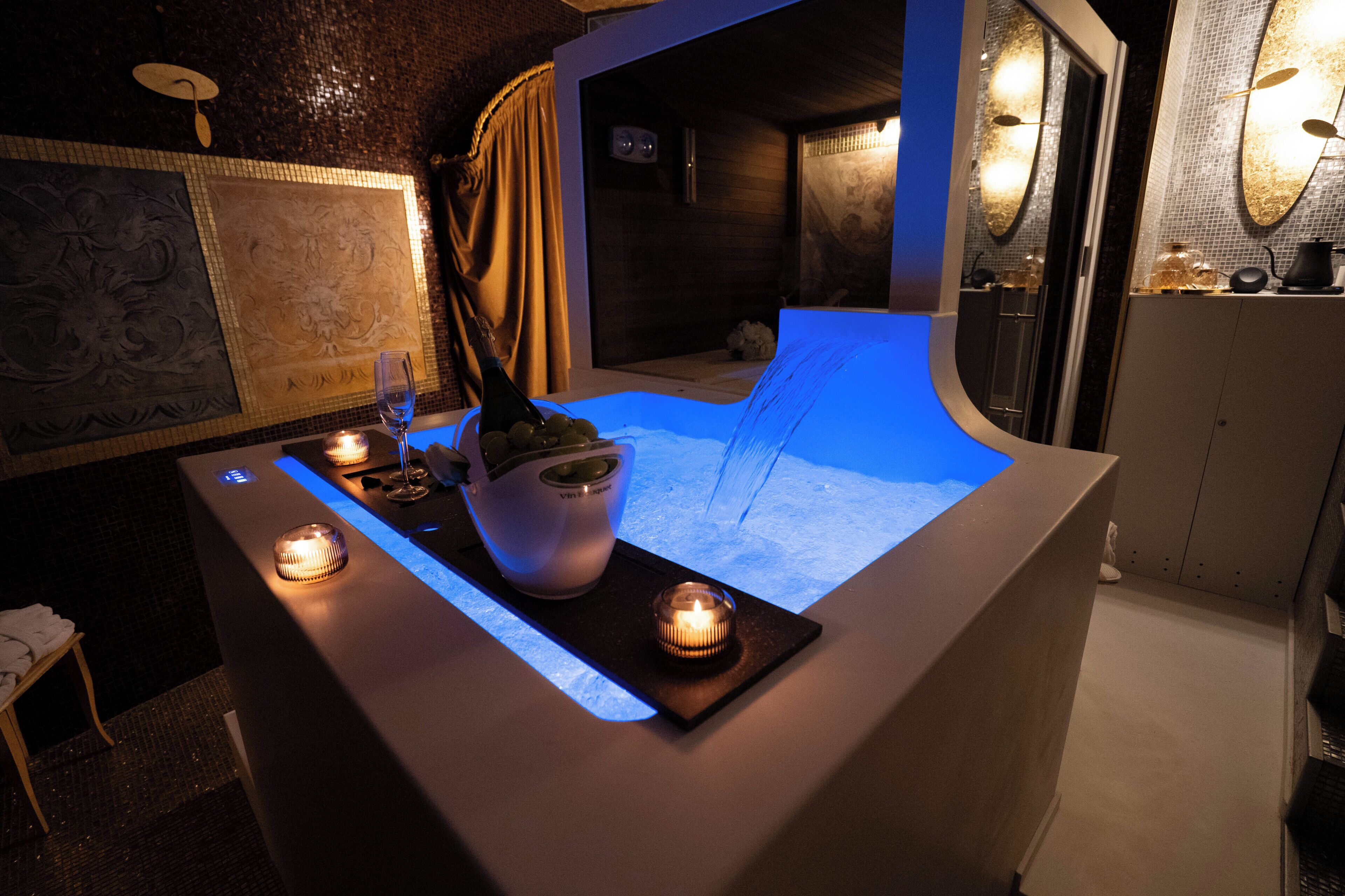Un'area benessere con pavimento riscaldato, una bottiglia di champagne e candele.