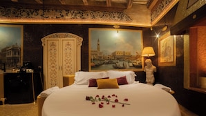 A hotel room with a large bed, a painting of Venice, a statue, and a decorative wall. - The Doge's Secret | Wellness Suite with Private Spa in Verona (Verona)
