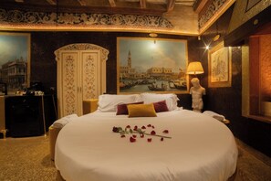 A hotel room with a large bed, a painting of Venice, a statue, and a decorative wall. - The Doge's Secret | Wellness Suite with Private Spa in Verona (Verona)