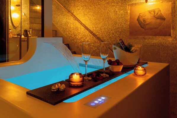 A bar area with two glasses of water, a candle, and a bottle of champagne.