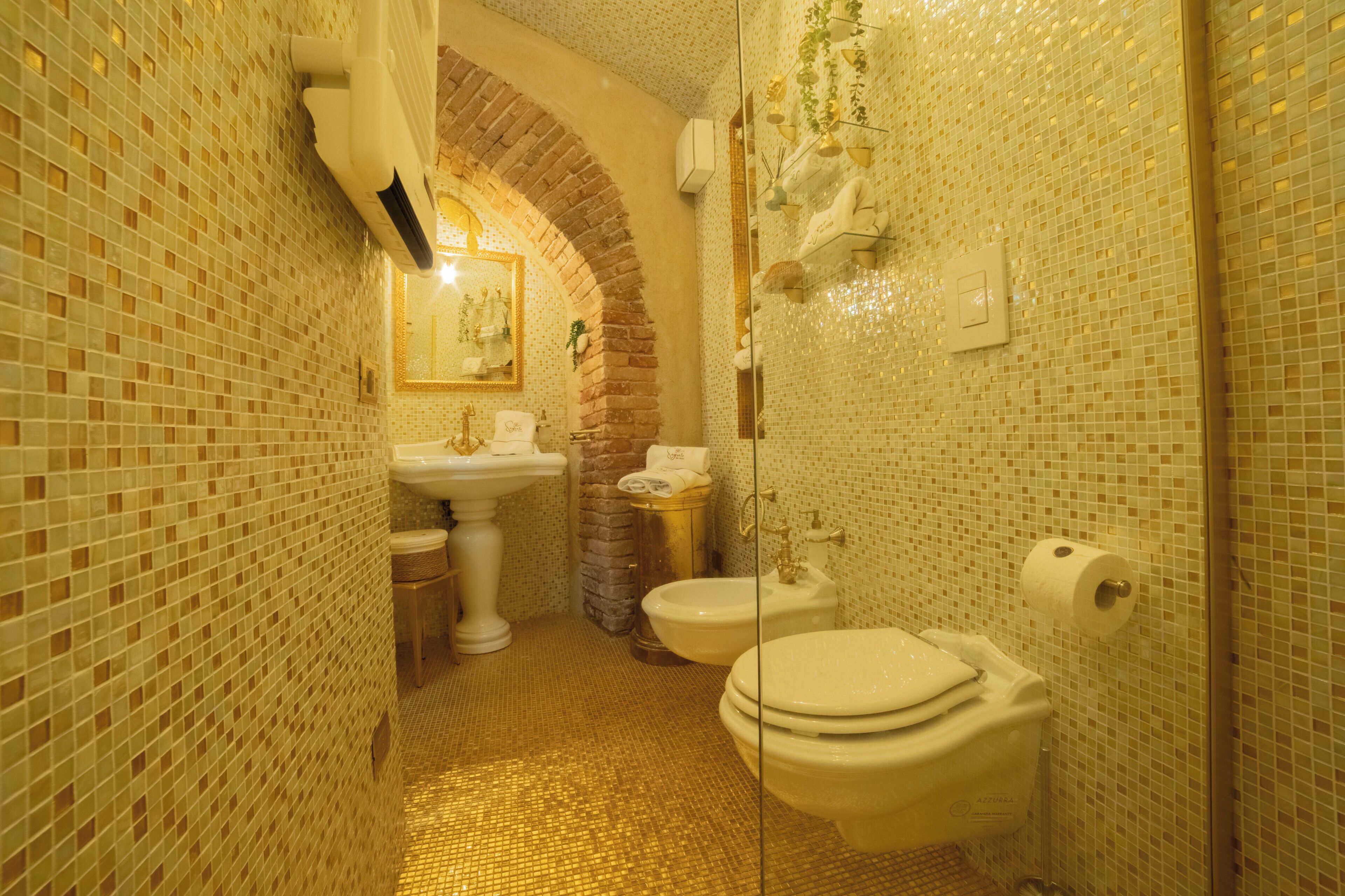 Une salle de bain avec un sol carrelé, un lavabo, des toilettes et un espace douche.