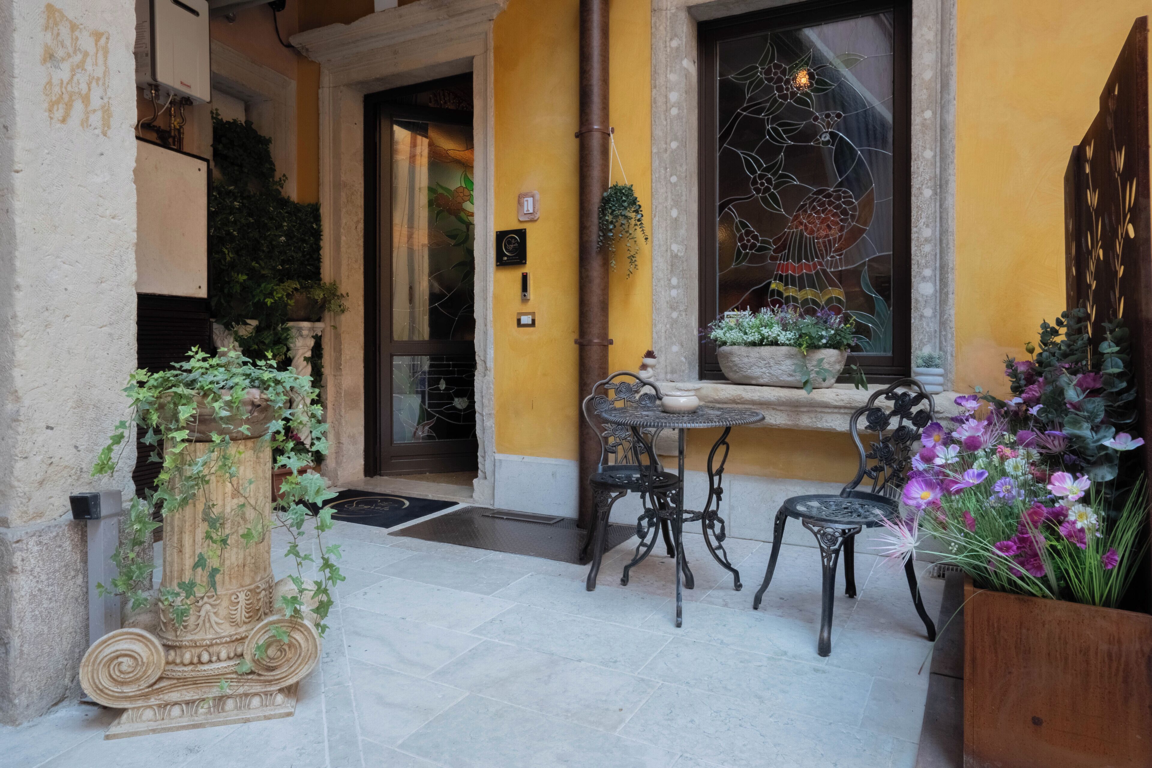 Un espace extérieur aménagé avec une table et des chaises, un vase décoratif et des plantes en pot.