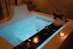 A bar area with a bar counter, two glasses, a bottle of champagne, and candles.
