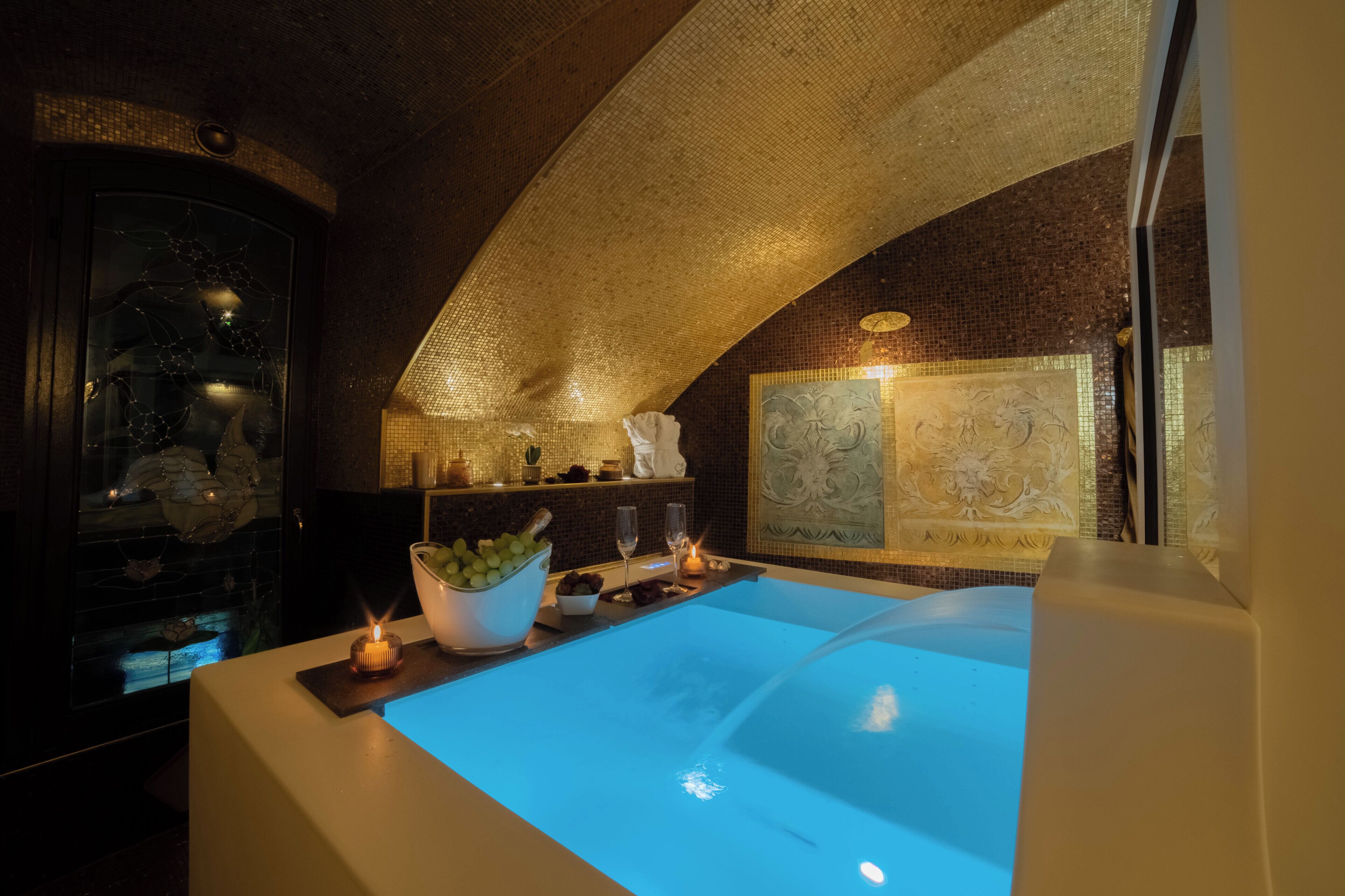 Une salle de bain moderne avec une grande baignoire, un mur décoratif et une petite table sur laquelle est posée une bougie.