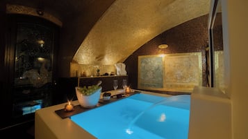 Une salle de bain moderne avec une grande baignoire, un mur décoratif et une petite table sur laquelle est posée une bougie.