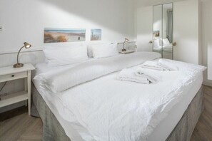 Ein Hotelzimmer mit einem großen Bett, einem Nachttisch mit Lampe, einem Spiegel und Bildern an der Wand.