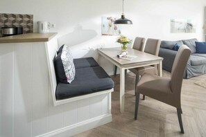 Ein modernes Wohnzimmer mit Sofa, Esstisch und Küchenzeile inklusive Geräte.