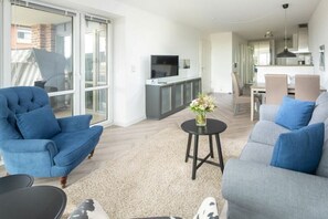 Ein modernes Wohnzimmer mit einer Couch, einem Sessel und einem kleinen Tisch mit einer Vase.