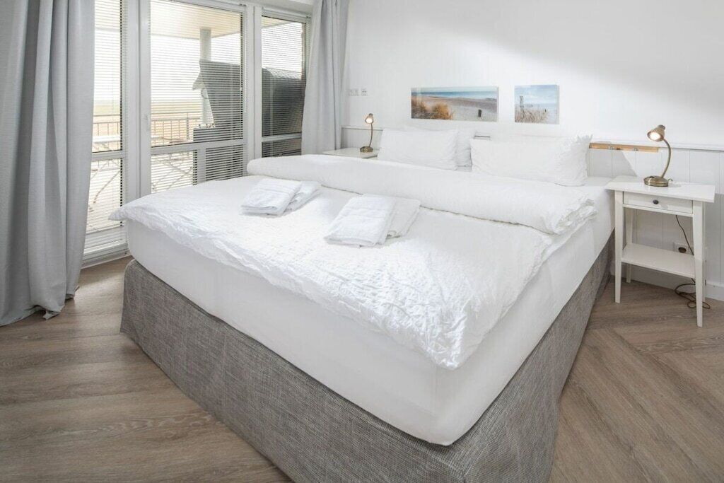 Une chambre d’hôtel avec un grand lit, une table de chevet avec une lampe et une vue sur l’extérieur par la fenêtre.