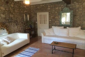 Ein Zimmer mit Steinwand, einem weißen Sofa, einem Holztisch und einer Tür.