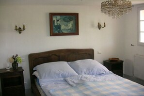 Quarto com cama de madeira, um quadro na parede, um candelabro e luminárias de cabeceira.