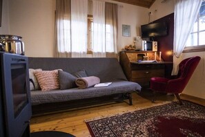 A cozy living room with a sofa, a red chair, a television, and a wooden floor. - directly on the lake in Sweden (Ulricehamn)