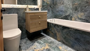Une salle de bain moderne équipée de toilettes, d’un meuble-lavabo et d’une baignoire.