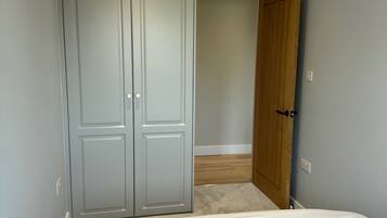 A bedroom with a bed, a grey wardrobe, and a wooden door.