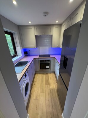 Eine kompakte Küche mit Waschmaschine, Backofen und Kühlschrank.