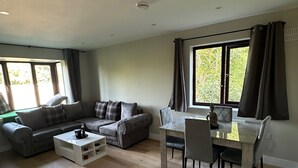Un grand espace de vie comprenant un canapé, une table à manger avec des chaises et une fenêtre avec des rideaux.