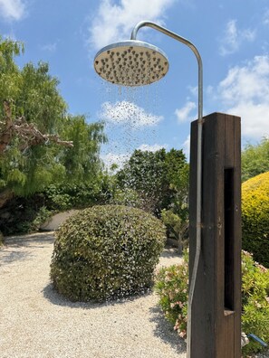A garden with a metal showerhead, a wooden post, and a gravel path. - Family Villa With Large Pool, Home Away From Home (Pegeia)