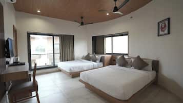 Habitación de hotel con dos camas, un escritorio con silla, televisor y ventilador de techo.