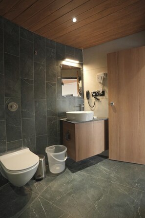 Een moderne badkamer met toilet, bidet, wastafel en spiegel.
