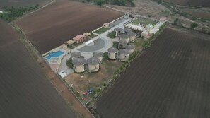 An aerial view of a property with a swimming pool, multiple cylindrical structures, and a landscaped area with a playground.