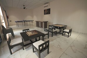 Een kamer met een schaaktafel, een tafelvoetbaltafel en een biljarttafel.