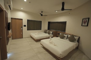 A hotel room with two beds, a door, a ceiling fan, and a window with curtains.