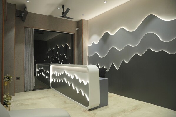 A reception area with a modern design, including a reception desk and a wall with a wave-like light pattern.