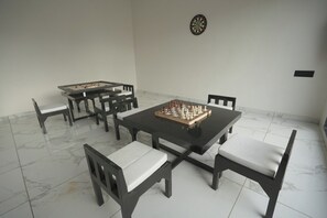 A dining area with a chessboard, a dartboard, and a foosball table.