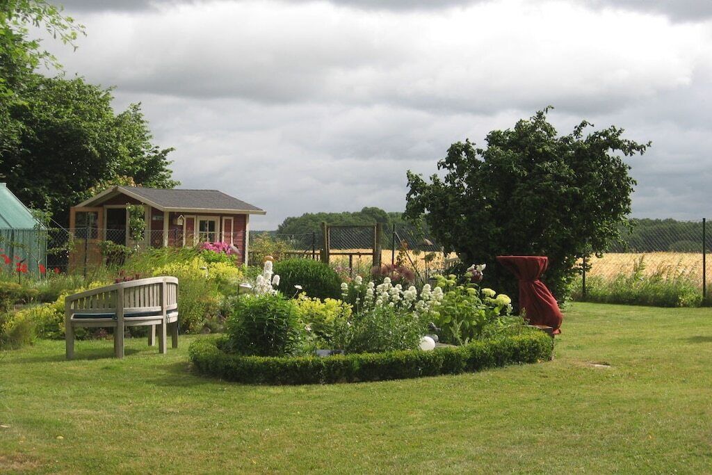 Ein Garten mit einer Bank, einem kleinen Haus und einem Baum.