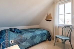 A bedroom with a bed, a chair, a window, and a sailboat decoration. - Holiday home with 2 bedrooms (18445 Kramerhof, Deutschland)