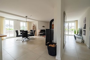 A spacious living area with a dining table, chairs, a black cabinet, and a fireplace. - Holiday home with 2 bedrooms (18445 Kramerhof, Deutschland)