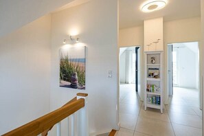 A hallway with a wooden handrail, a wall-mounted light fixture, and a bookshelf. - Holiday home with 2 bedrooms (18445 Kramerhof, Deutschland)