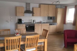 Eine kleine Küche mit Holzausstattung, einer Mikrowelle und einer Essecke mit Holzhöckern.