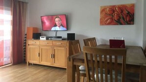 Habitació amb televisió, un quadre, un armari de fusta i una taula de dinar.
