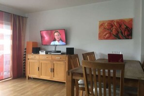 Una habitación con televisión, un cuadro, un aparador de madera y una mesa de comedor.
