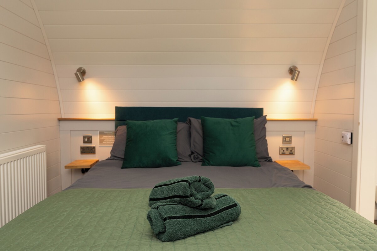 Habitació amb un llit, dues taules de nit, un radiador i llums penjades a la paret.