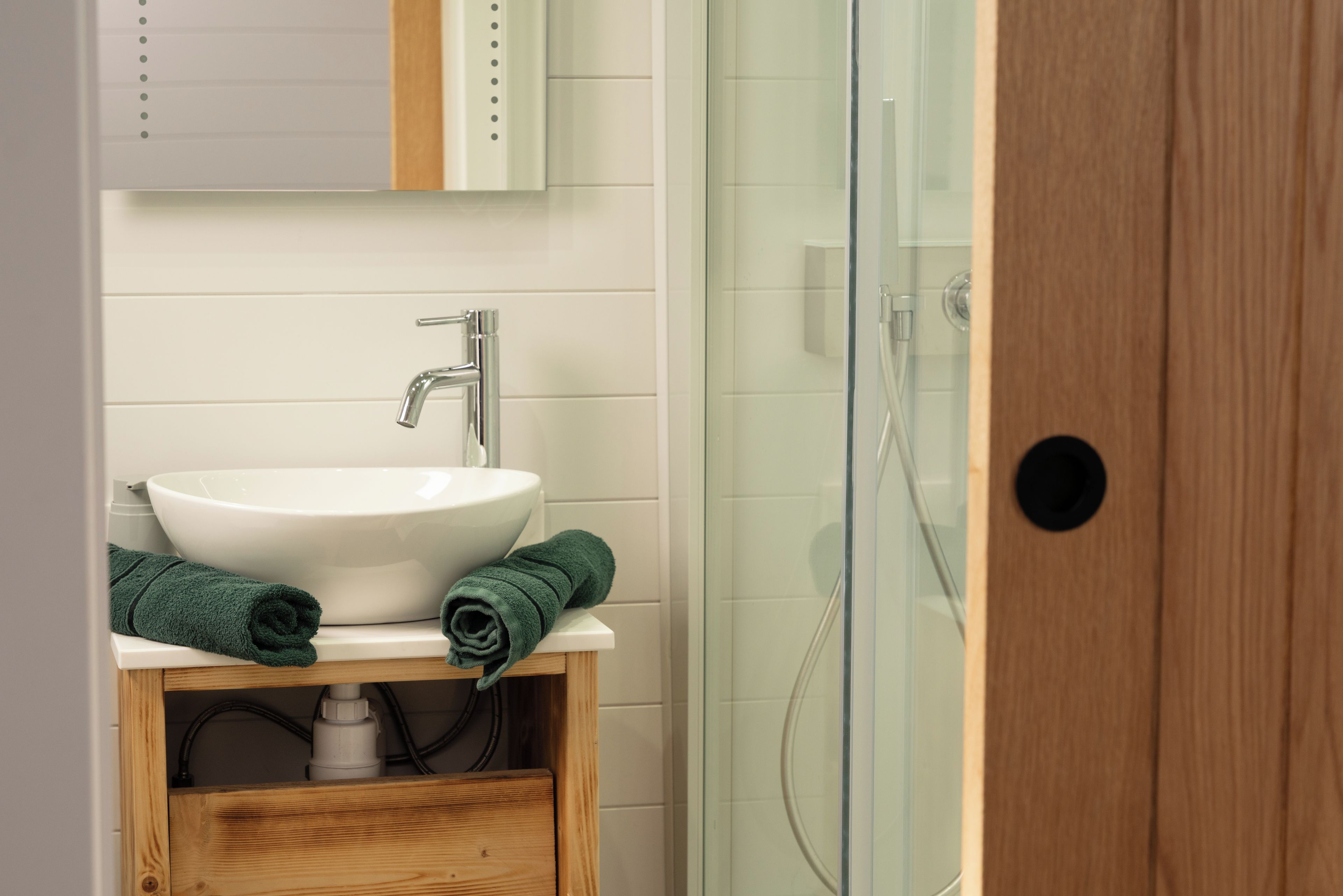 A bathroom with a white sink, a wooden cabinet, and a glass shower enclosure.