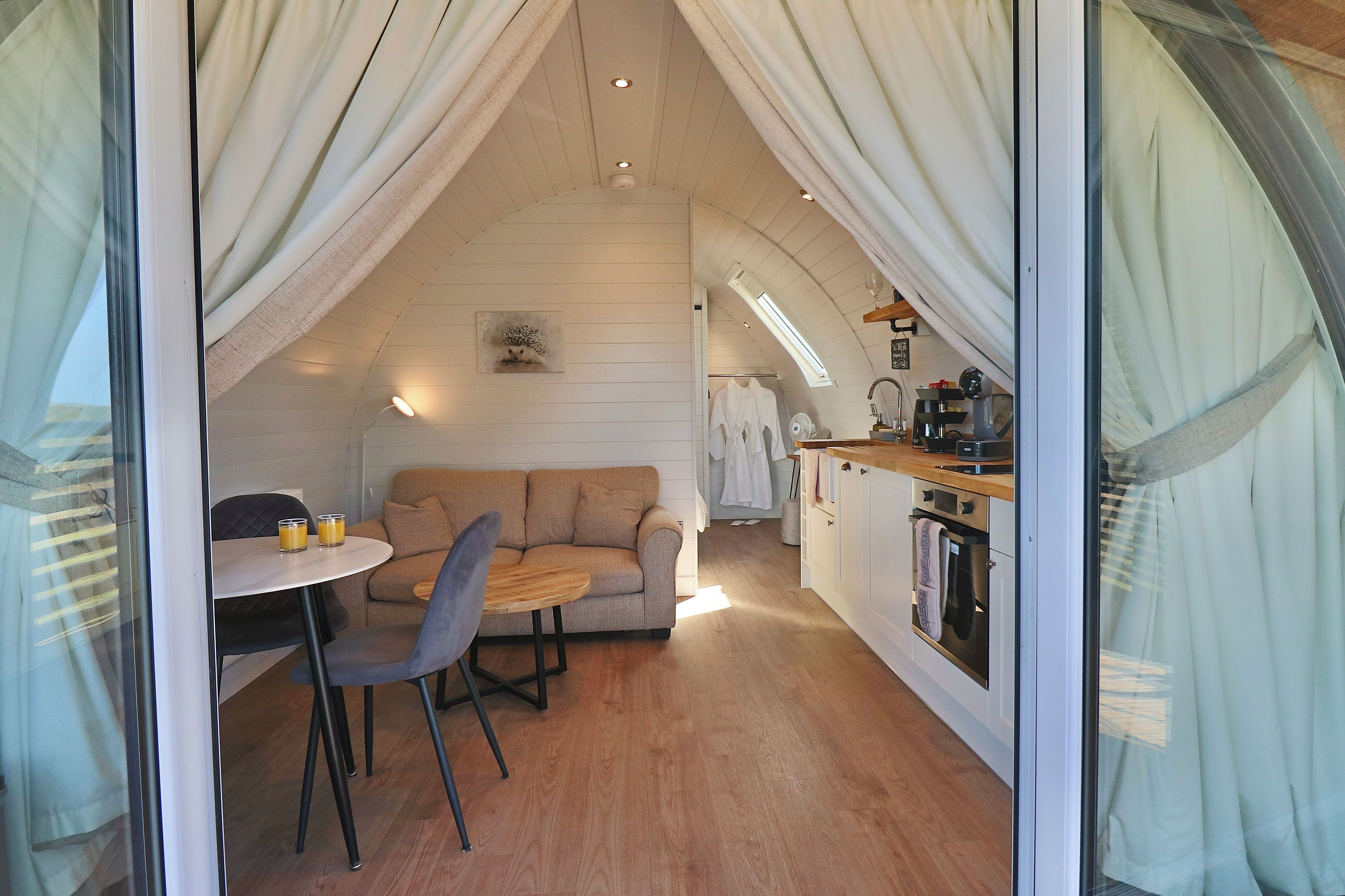 A cozy, compact living space with a kitchenette, a dining area with a table and chairs, and a sofa.