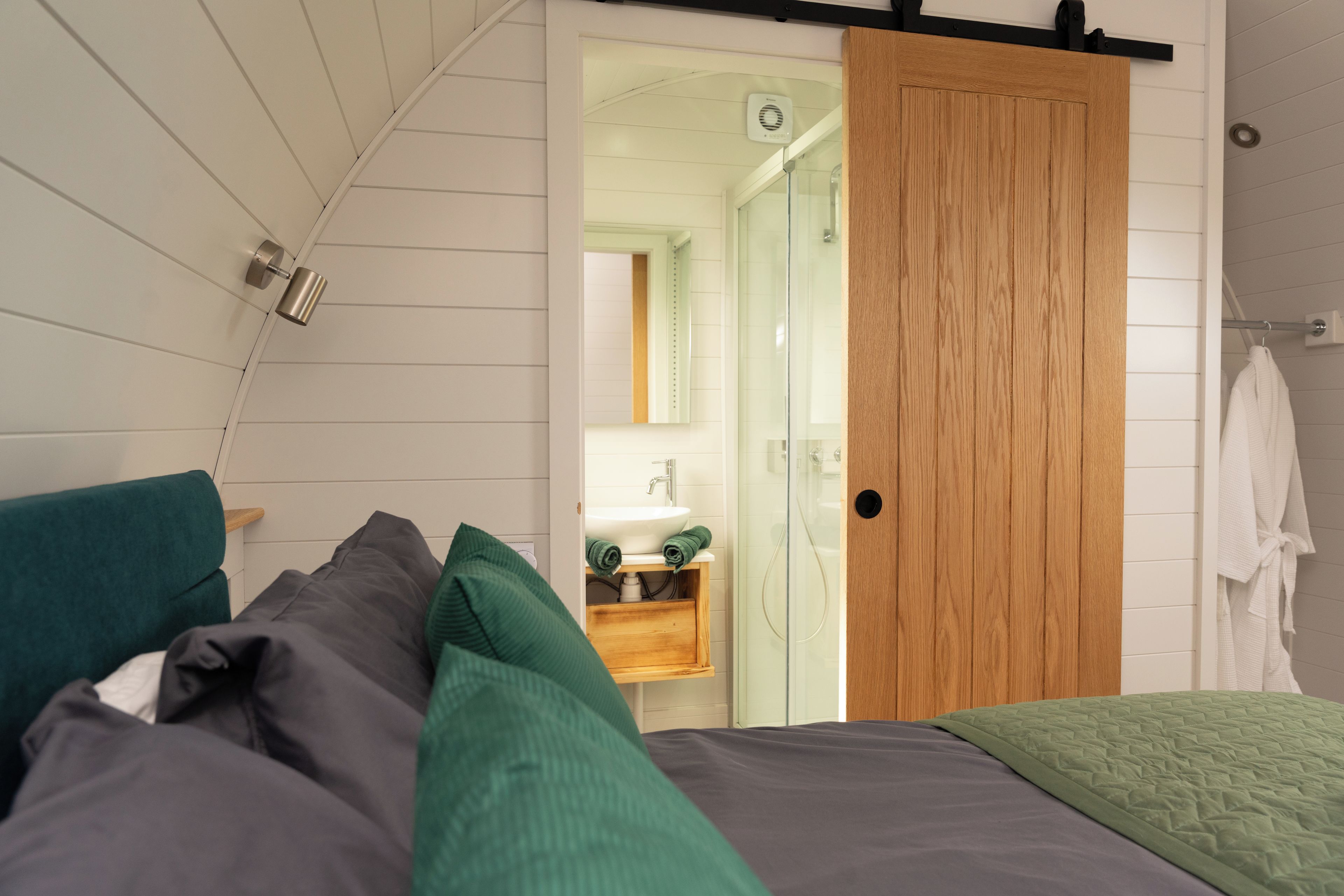 Un dormitorio con una cama, una puerta de madera y un baño visible a través de una puerta abierta.